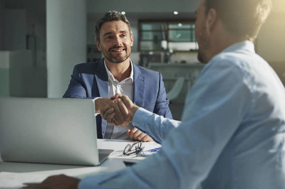 Dos hombres de negocios dándose la mano en una oficina./Foto: iStock.