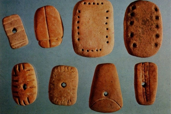 These perforated tokens with incised rectangles were probably strung together.
